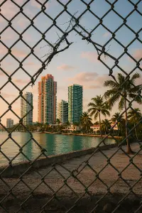 Punk díra v pletivu přes ni pohled na luxusní čtvrť miami vice budov palmy. Pohled z chudoby do bohatství foto