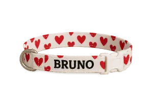 Bílý obojek s červenýma srdíčkama a nápisem "Brnuno"
