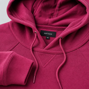 A close-up studio photograph of a premium, deep magenta-pink textured cotton-blend pullover hoodie. The focus is sharp o