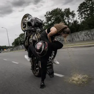 Motorka co jede po zadním kole a šahá rukou na zem a na spolujezdci blije holka na zem zvratky